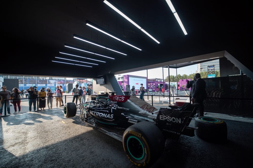 A Mercedes-AMG Formula 1 car on display in a lounge under linear lights